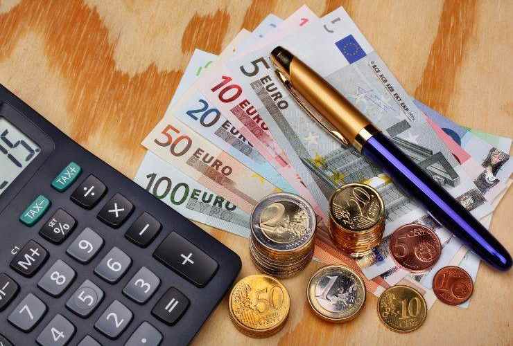 Calcolatrice con banconote e monete in euro